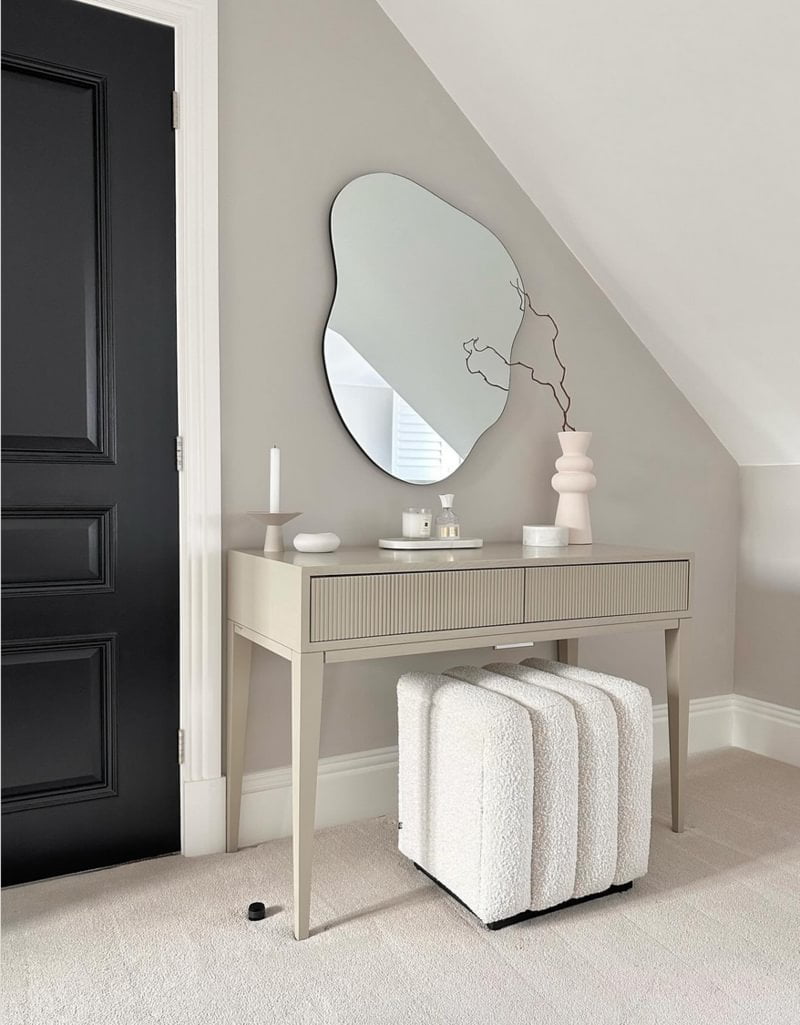 Neutral colored dressing table with abstract mirror and wool stool