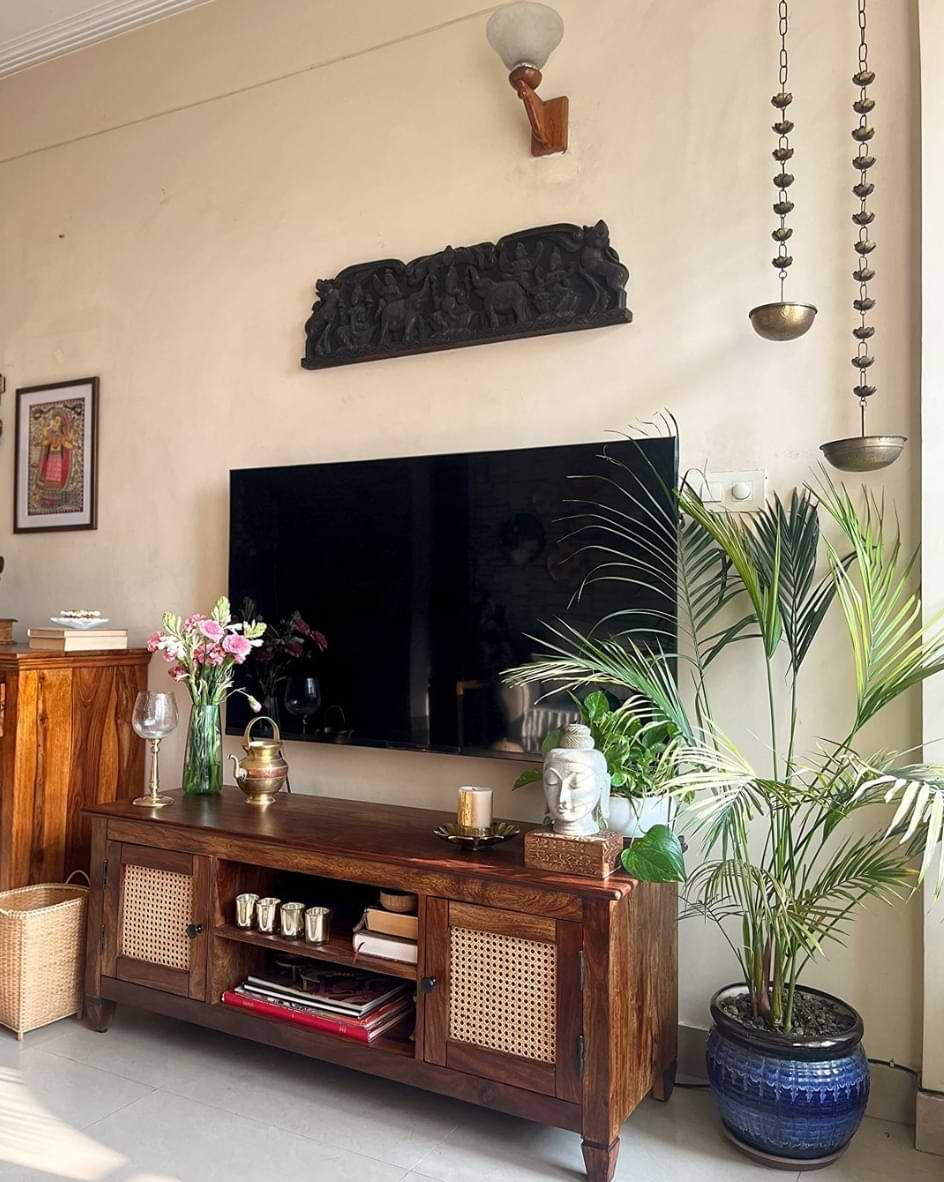 A living room with a wooden tv stand, a plant next to it, and a wall mounted tv