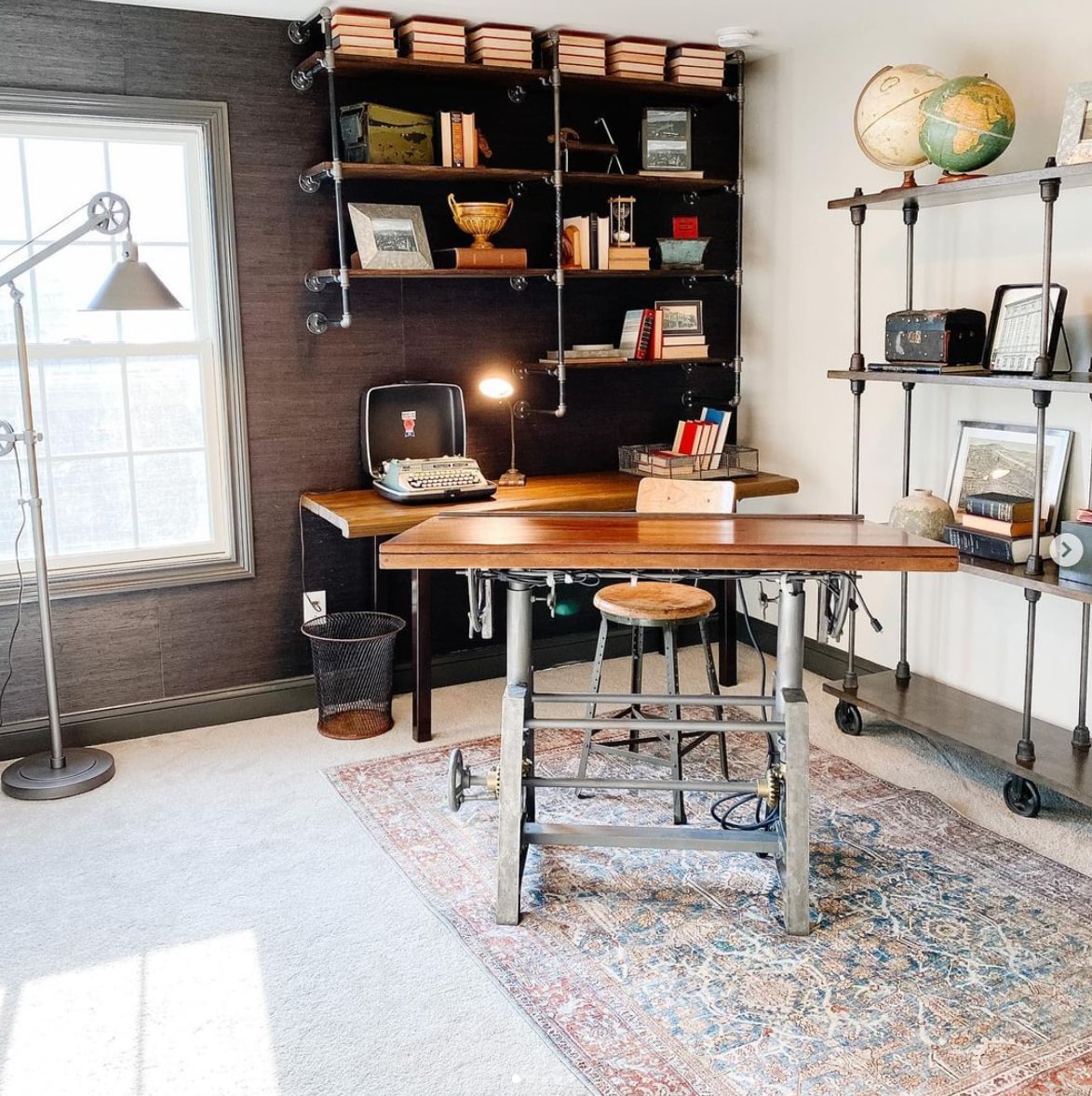 An industrial themed office with metal shelving and a wooden desk