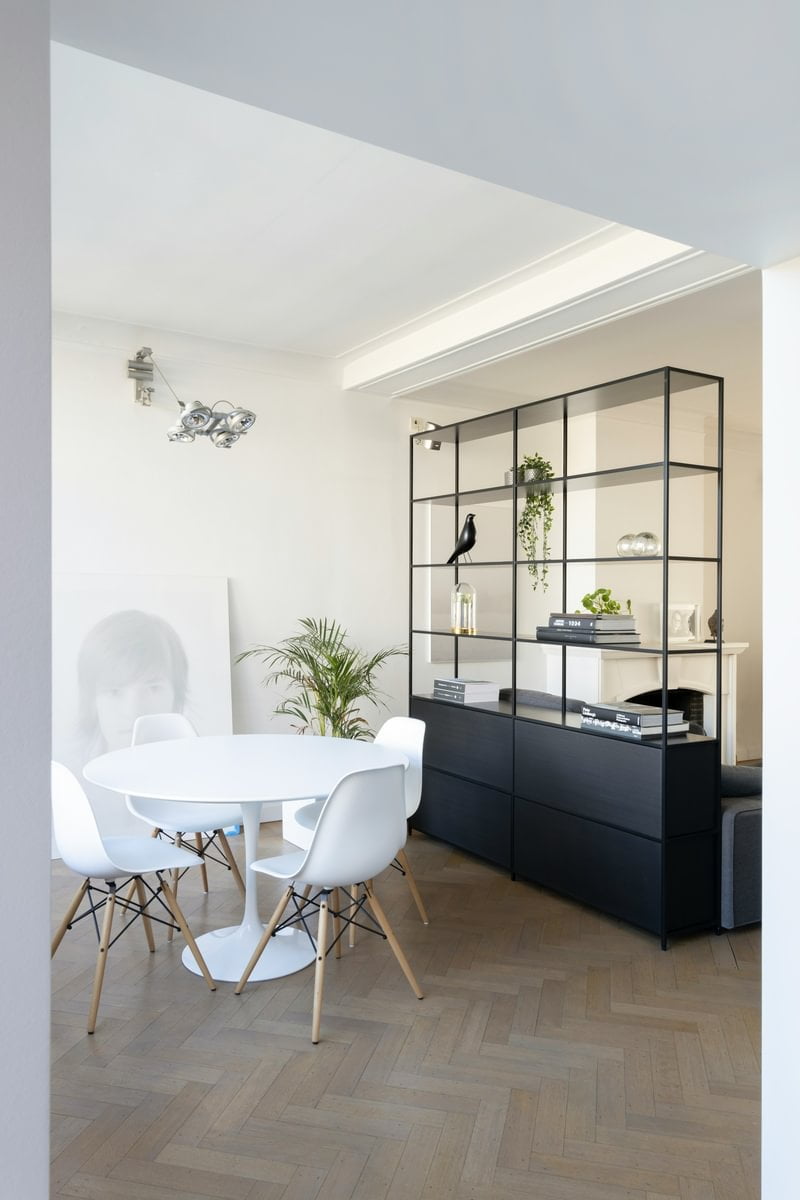 A living room dining area separated by tall black shelving
