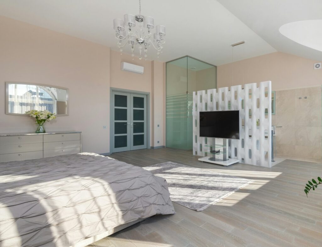 Open plan bedroom with a white screen separating the bedroom from the bathroom area