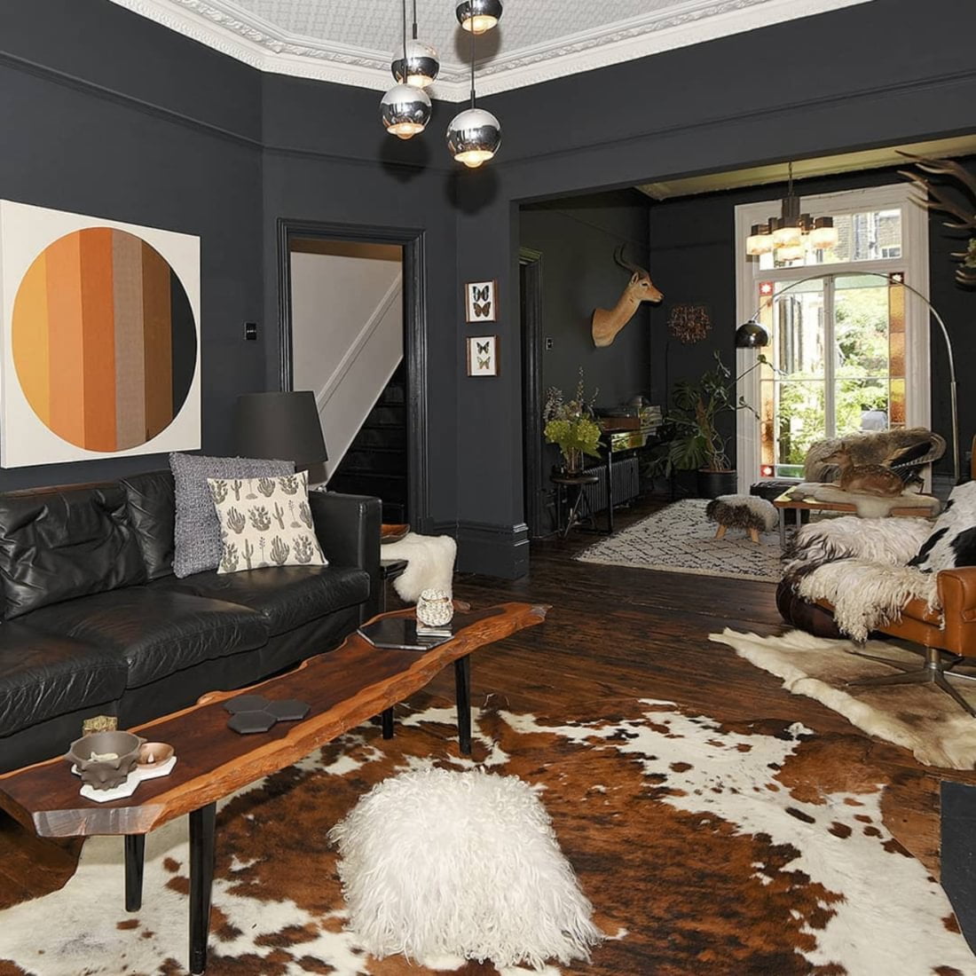 Living room with dark grey walls, bench style coffee table and cowhide rug