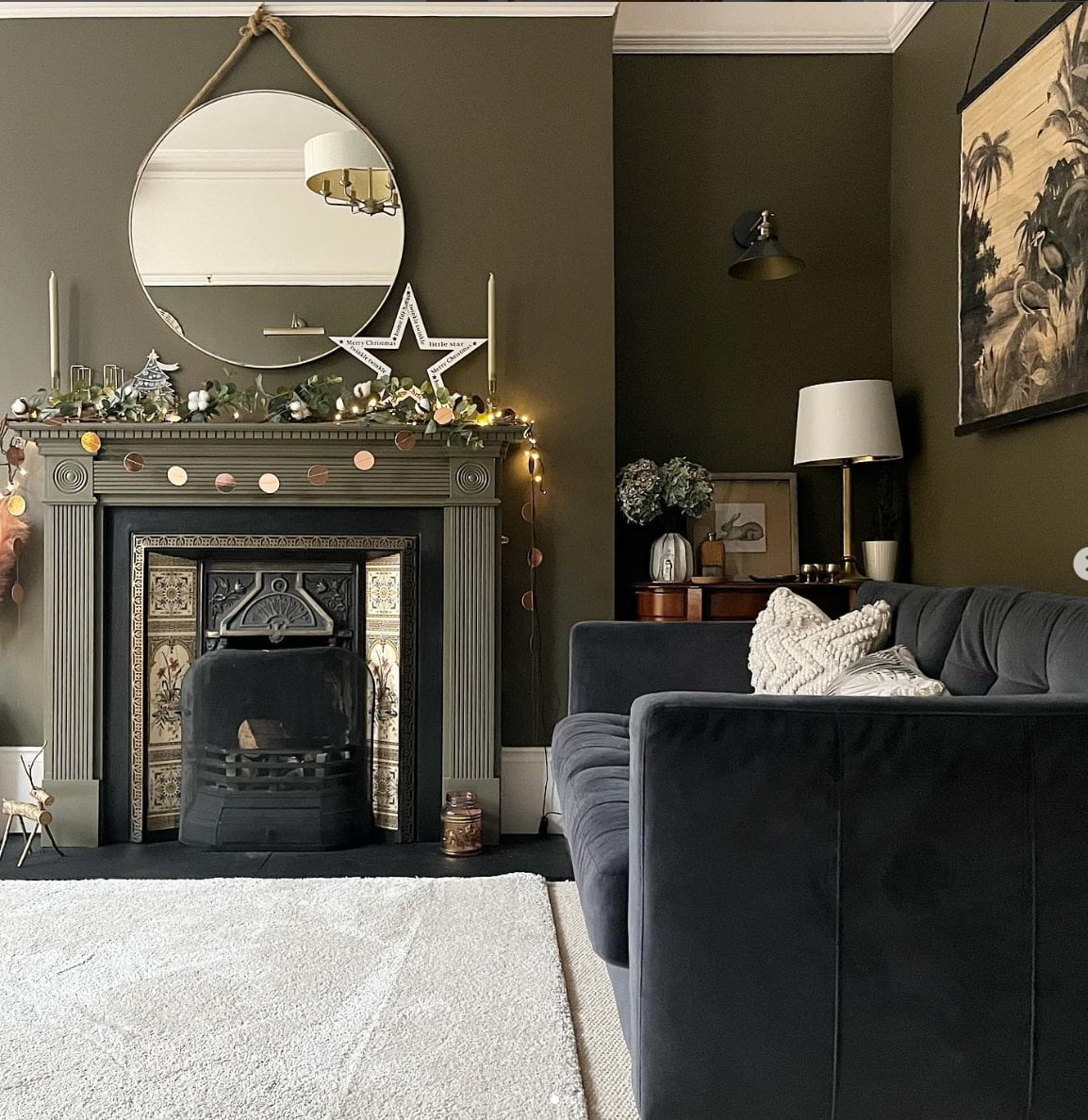 A living room with a dark green wall, Christmas decorations and a dark gray sofa