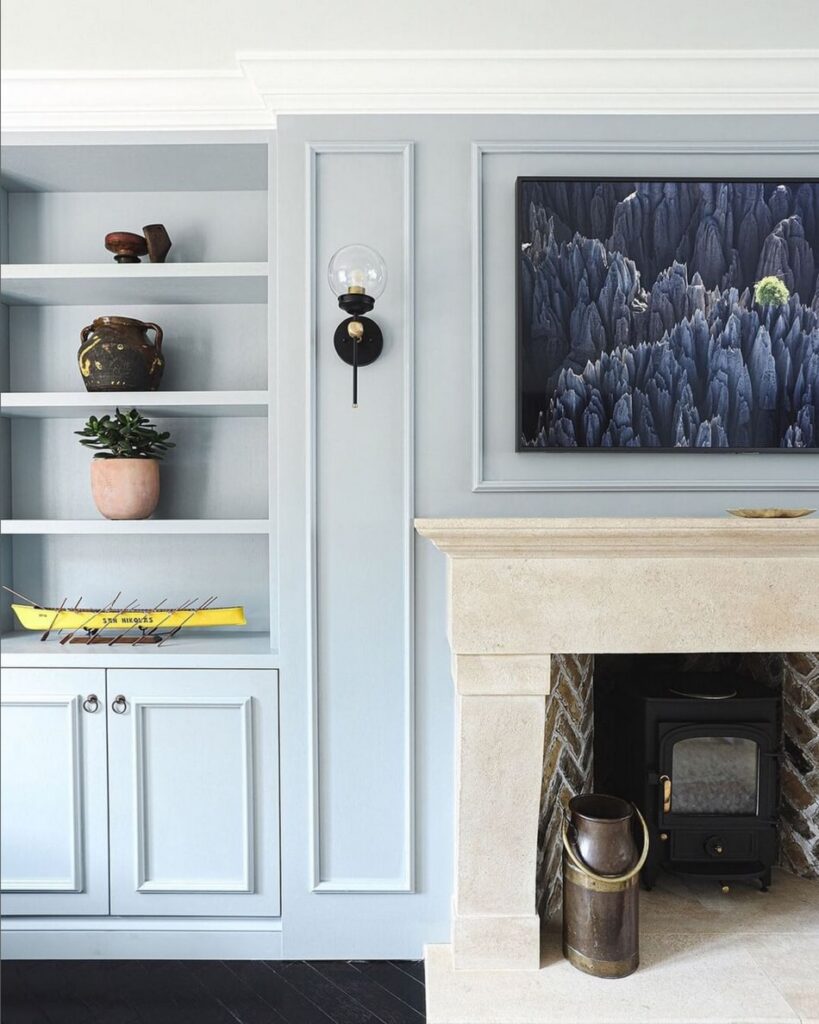 Media wall painted light blue with alcove shelving, a mounted TV and paneling throughout