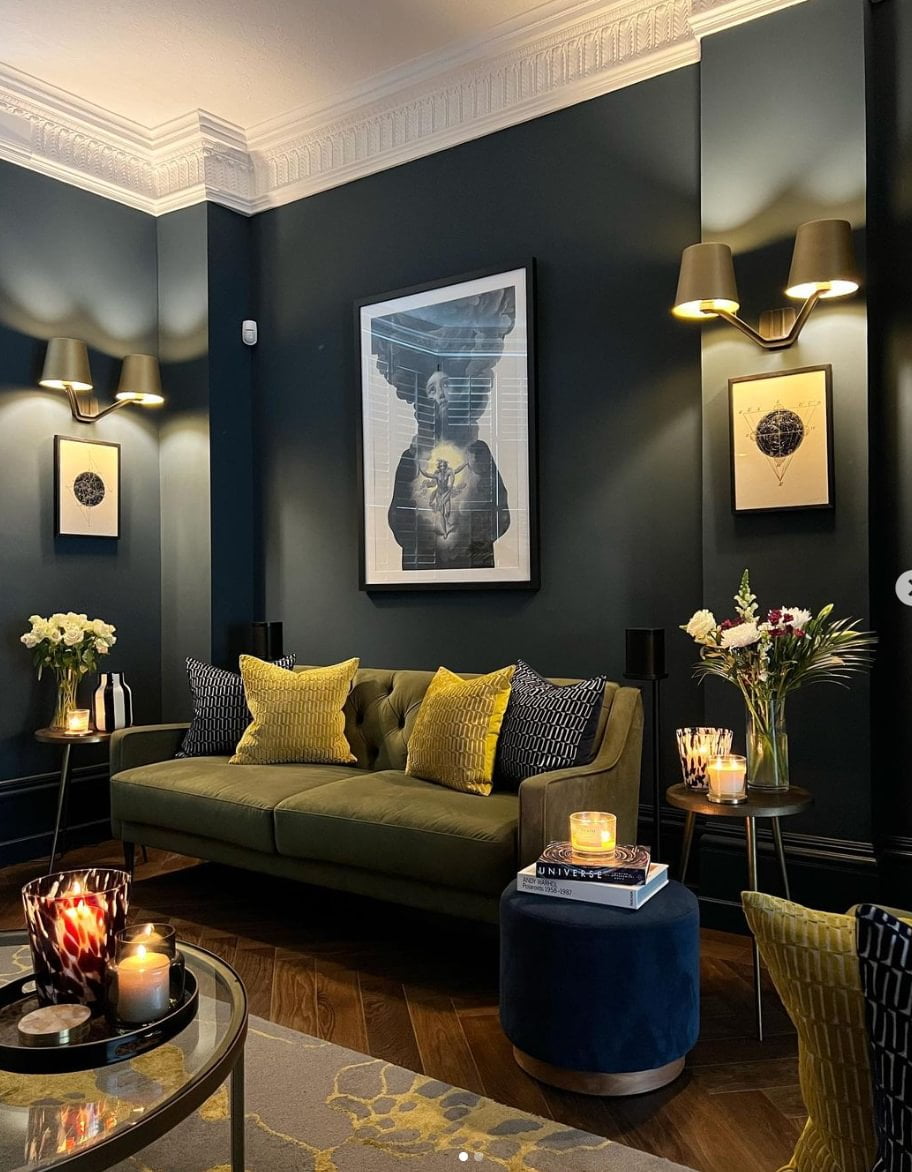 Dark navy blue walled living room with green sofa and wooden floor